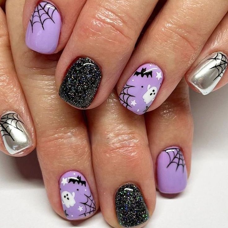 Playful Halloween Nail Design: Lavender Base with Spiderwebs, Ghosts, and Bats, Accented by Glittery Black and Silver.