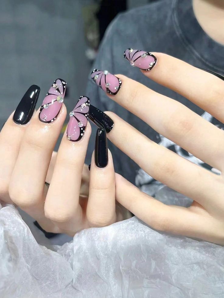 Stylish Black and Pastel Pink Nail Art with Butterfly Patterns and Gem Accents