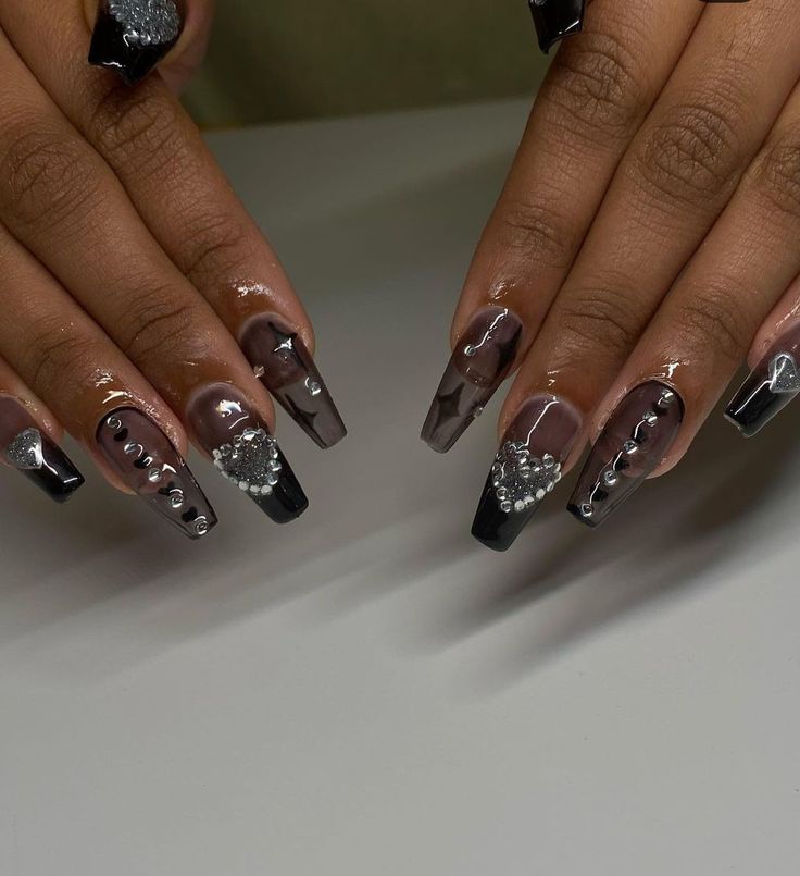 Elegant Black and Nude Nail Design with Glamorous Embellishments and Artistic Patterns.