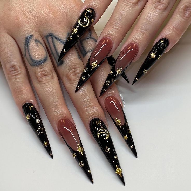 Bold Stiletto Nail Art: Deep Black and Nude with Intricate Gold Celestial Patterns