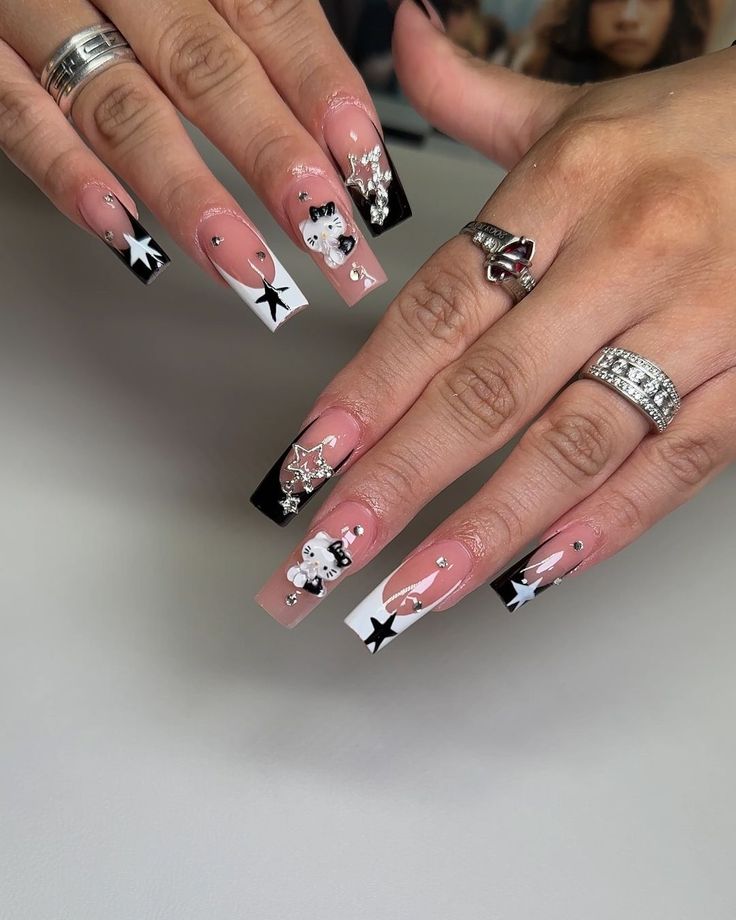 Chic Black and Nude Nail Design with Artistic Embellishments and Glossy Finishes.