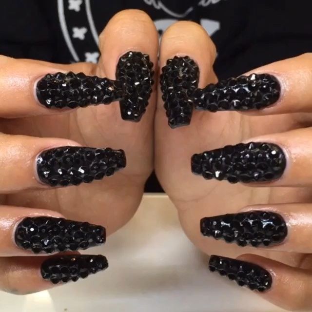 Dramatic Black Stiletto Nails with Textured Embellishments and Sparkling Crystals.