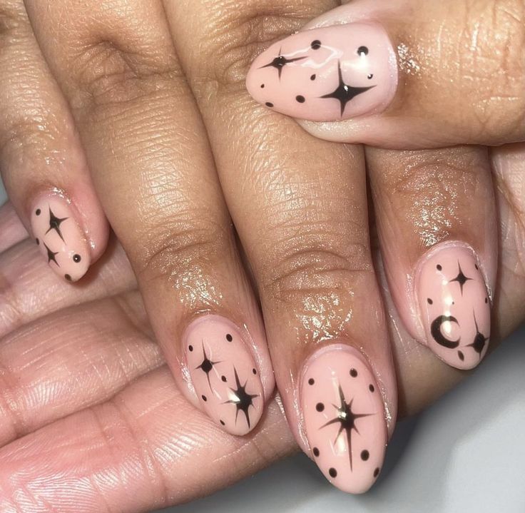 Celestial Nail Art: Soft Nude Base with Black Stars and Mystical Crescent Moon Accents.