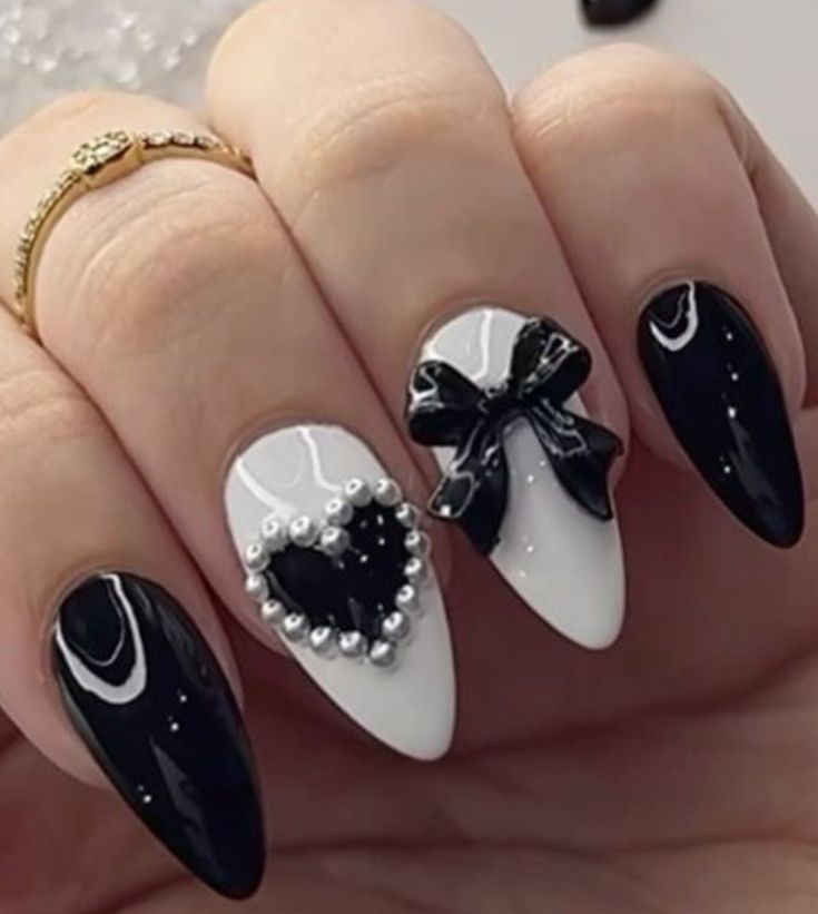 Sophisticated Black and White Nail Design with Heart, Pearls, and Bow Accents.