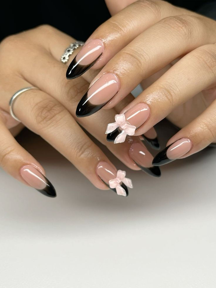 Chic Nude and Black Nail Design with Delicate Pink Bows for a Sophisticated Touch.