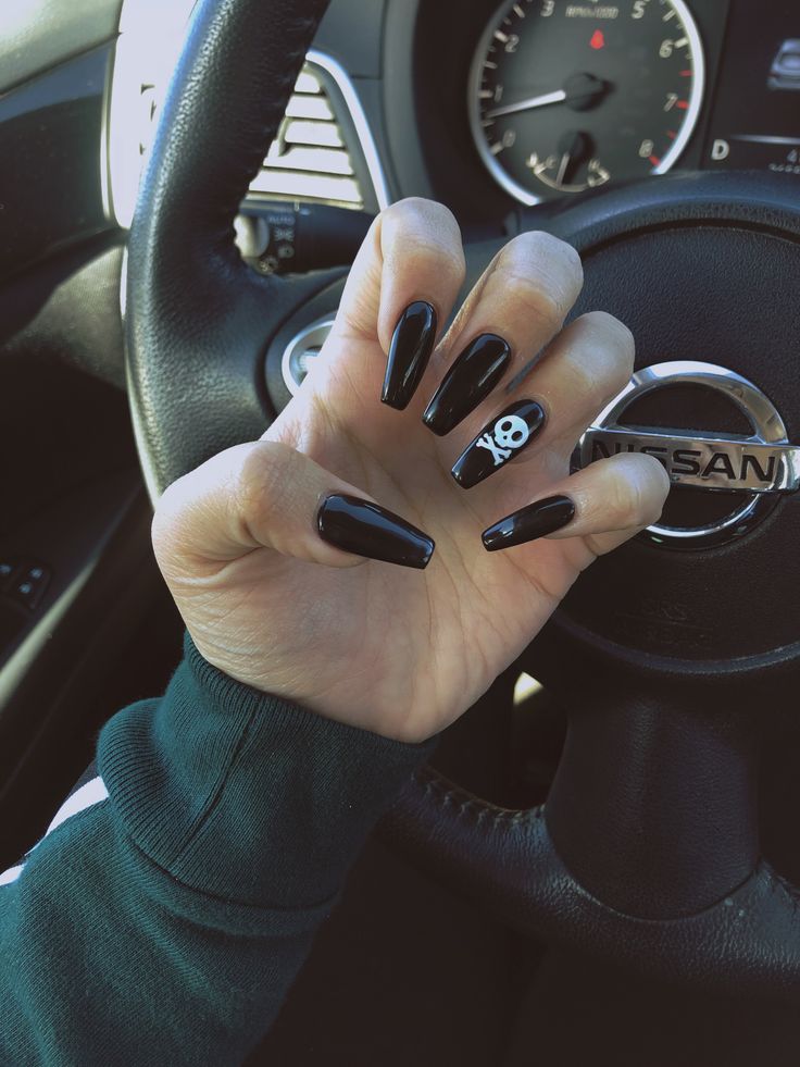 Edgy Glossy Black Nails with Playful Skull Motif for a Modern Aesthetic