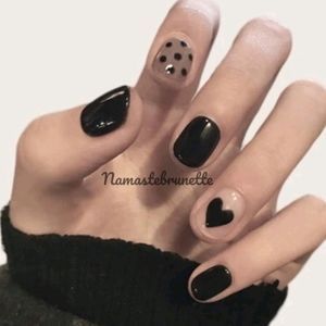 Chic Nail Design: Glossy Black Meets Soft Beige with Playful Dots and Whimsical Hearts.