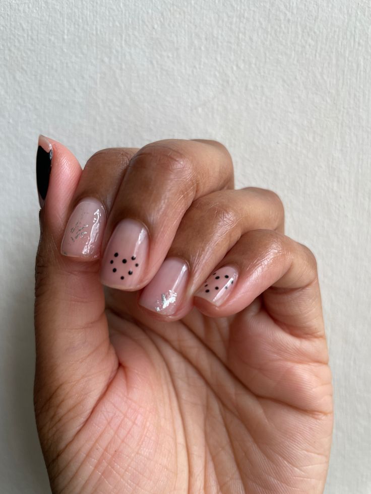 Chic Nude Nail Design with Delicate Black Polka Dots for Versatile Elegance.