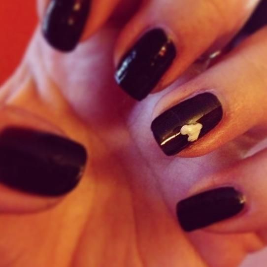 Chic Black Nail Design with Subtle White Accents and Charming Heart Motif.