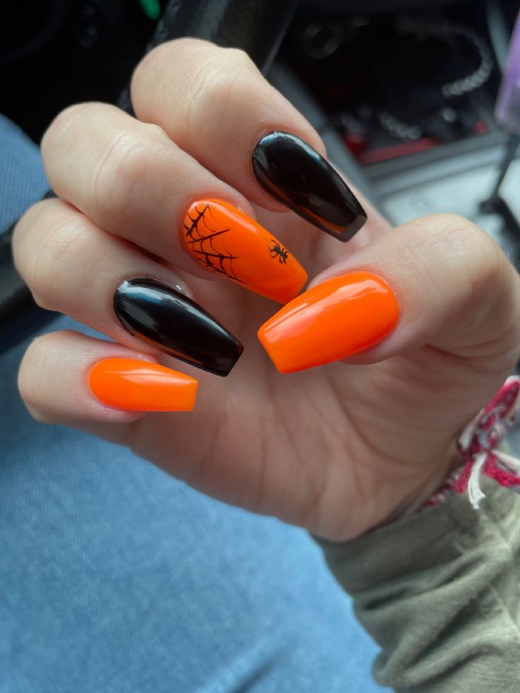 Bold Halloween Nail Design: Orange and Black with Spider Web Accents in Dramatic Almond Shape.