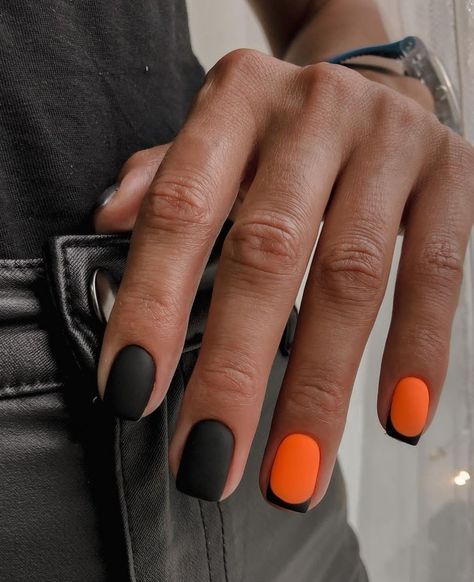 Striking Matte Black and Vibrant Orange Nail Design with Unique Accent Detail.