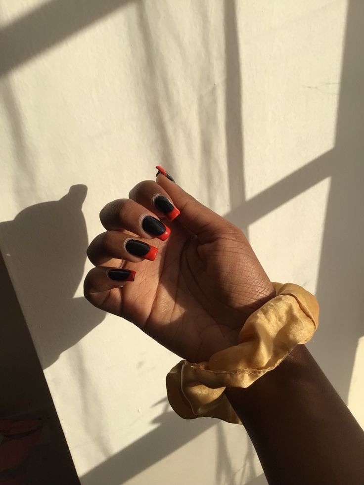 Sophisticated Nail Design: Matte Black Polish with Vibrant Red Tips and Trendy Scrunchie Accent.