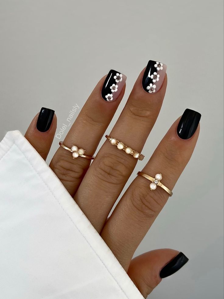 Elegant Black Floral Nails Enhanced by Gold Rings: A Chic, Whimsical Manicure.