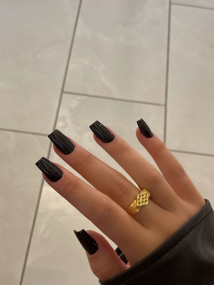 Chic Black Manicure with Long Glossy Nails and Golden Ring for an Elegant Statement.