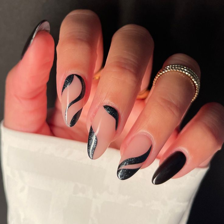 Elegant Black and Nude Nail Design with Sleek Waves and Glitter Accents.