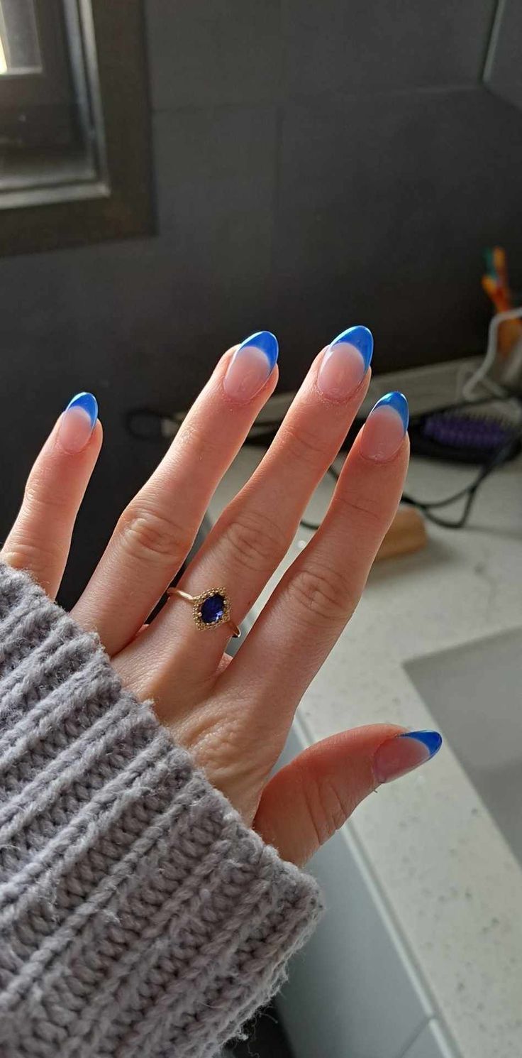 Chic French Manicure with Vibrant Blue Tips and Elegant Ring Accessory.