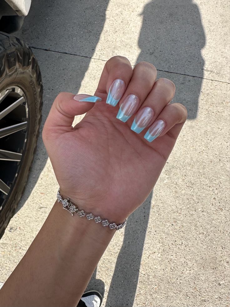 Chic Nail Design: Transparent Tips with Light Blue Ombre and Elegant Bracelet Accents.