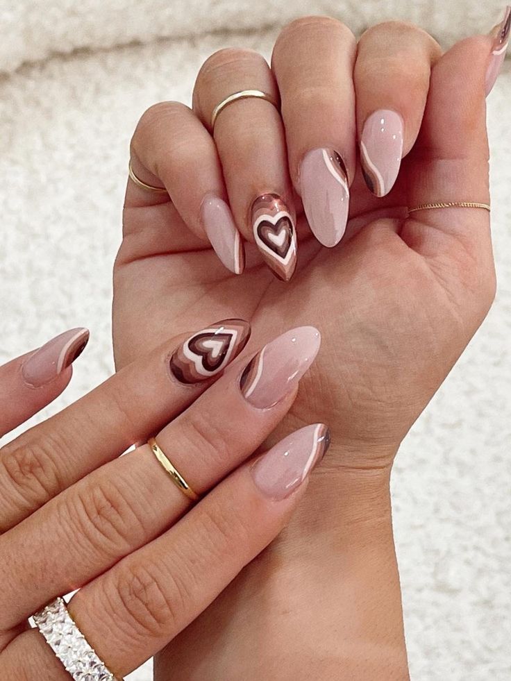 Romantic Nail Design: Soft Nude with Glossy Brown Heart Patterns and Chic Gold Accents.