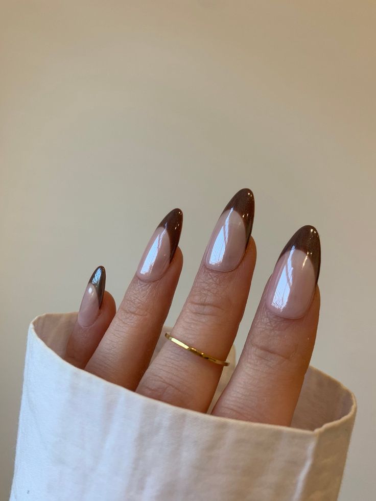 Chic Almond-Shaped Nails with Nude Base and Glossy Brown Tips, Enhanced by a Gold Ring.