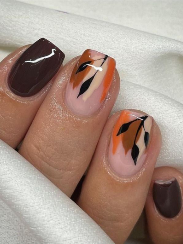 Elegant Autumn Nail Design: Warm Tones with Black Leaf Accents.