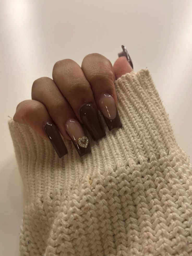 Sophisticated Chic Nail Design: Long Brown Nails with Elegant Nude Accent and Heart Embellishment.