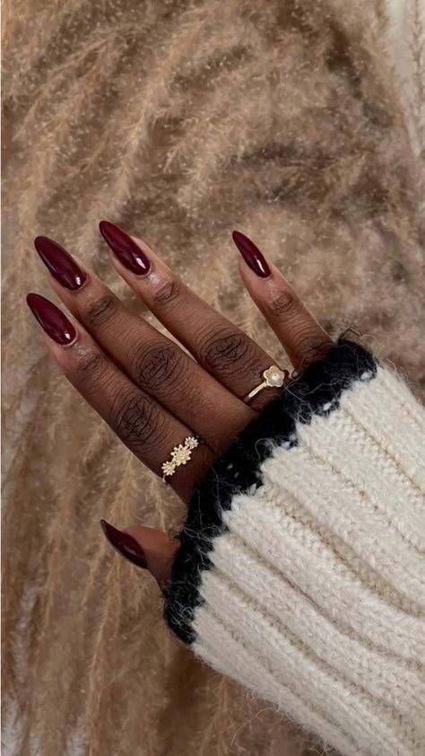 Sophisticated Burgundy Almond Nails Complemented by a Cozy Cream Sweater and Chic Rings.