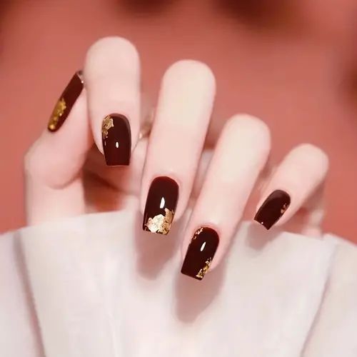 Sophisticated Dark Red Nails with Glamorous Gold Leaf Accents