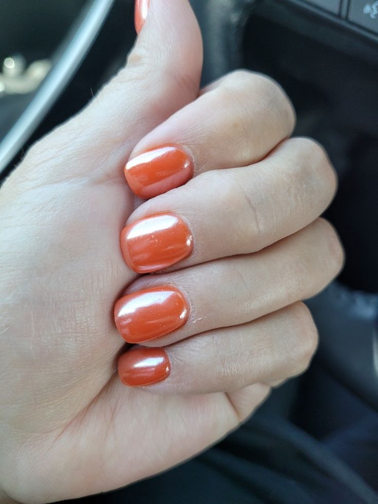 Vibrant Glossy Orange Manicure with Rounded Nail Shapes for a Polished Look.