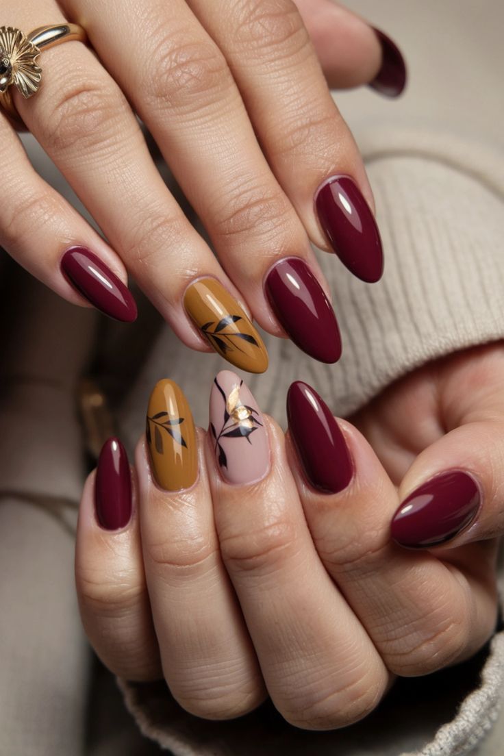 Sophisticated Nail Design Featuring Deep Burgundy and Warm Mustard with Intricate Leaf Patterns.