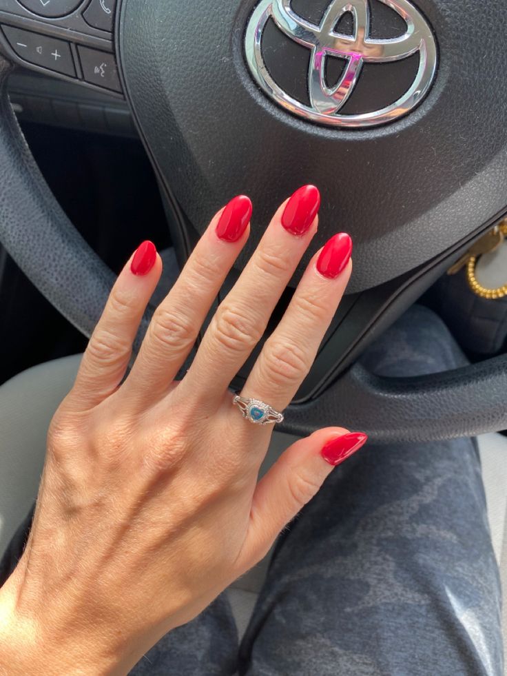 Chic Contrast: Bold Crimson Nails Enhance Sleek Car Interior Aesthetic