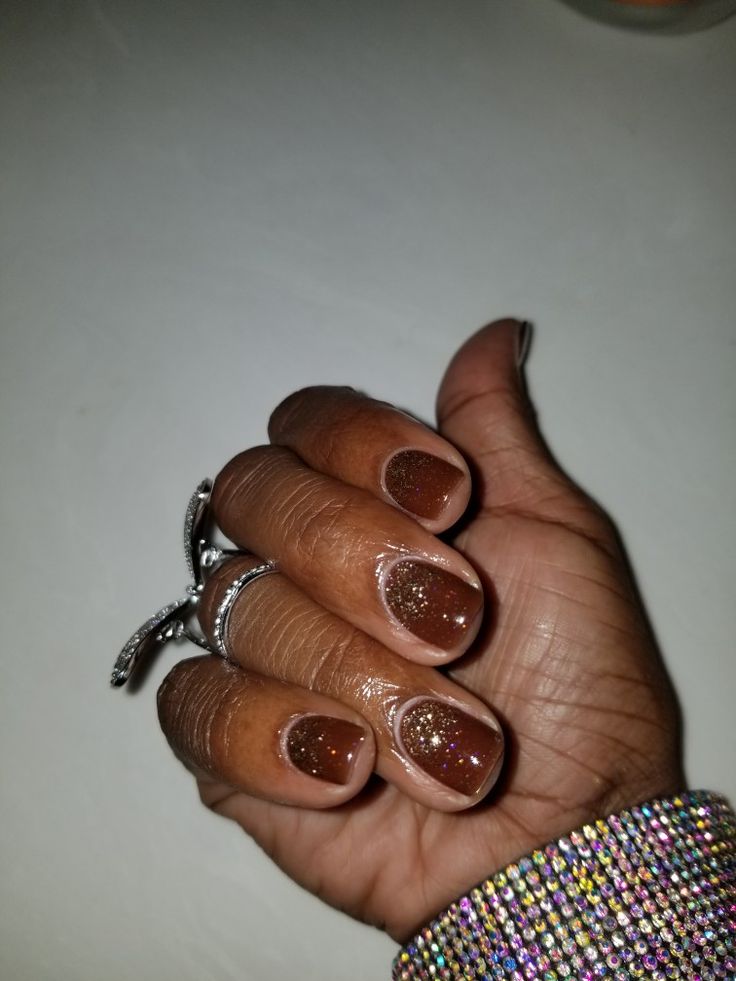 Elegant Glittery Brown Nail Design with Shimmering Finish and Complementing Accessories.