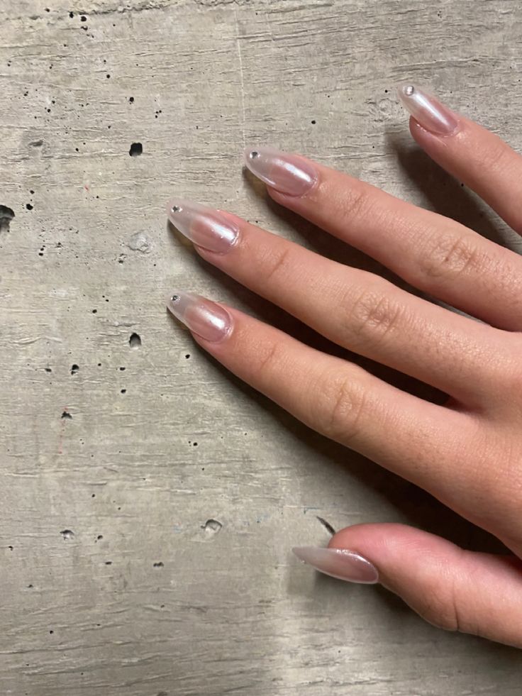 Chic Almond-Shaped Nude Nail Design with Sparkling Accents.