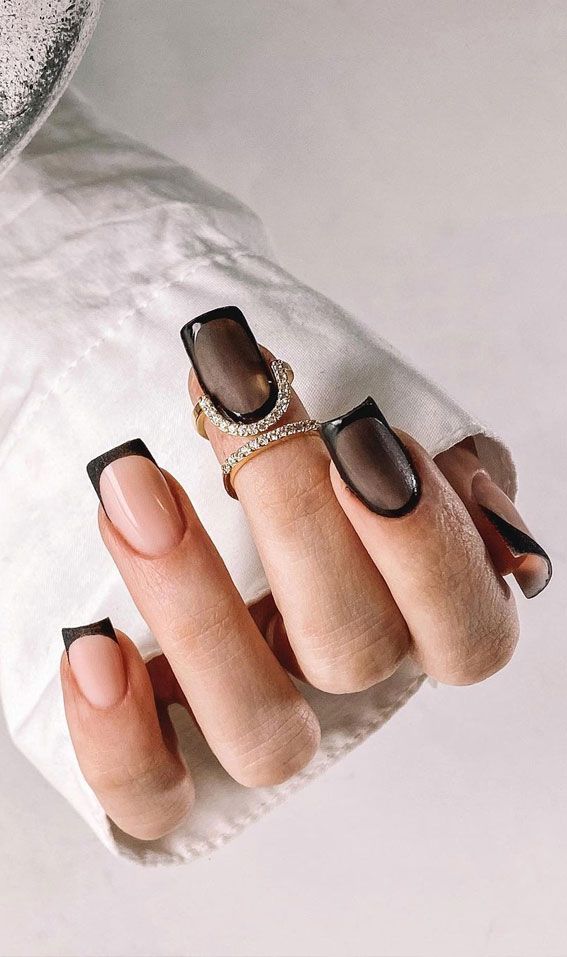 Edgy Chic Nail Design: Bold Black Tips on a Nude Base with Glossy Finish and Elegant Ring Accents.