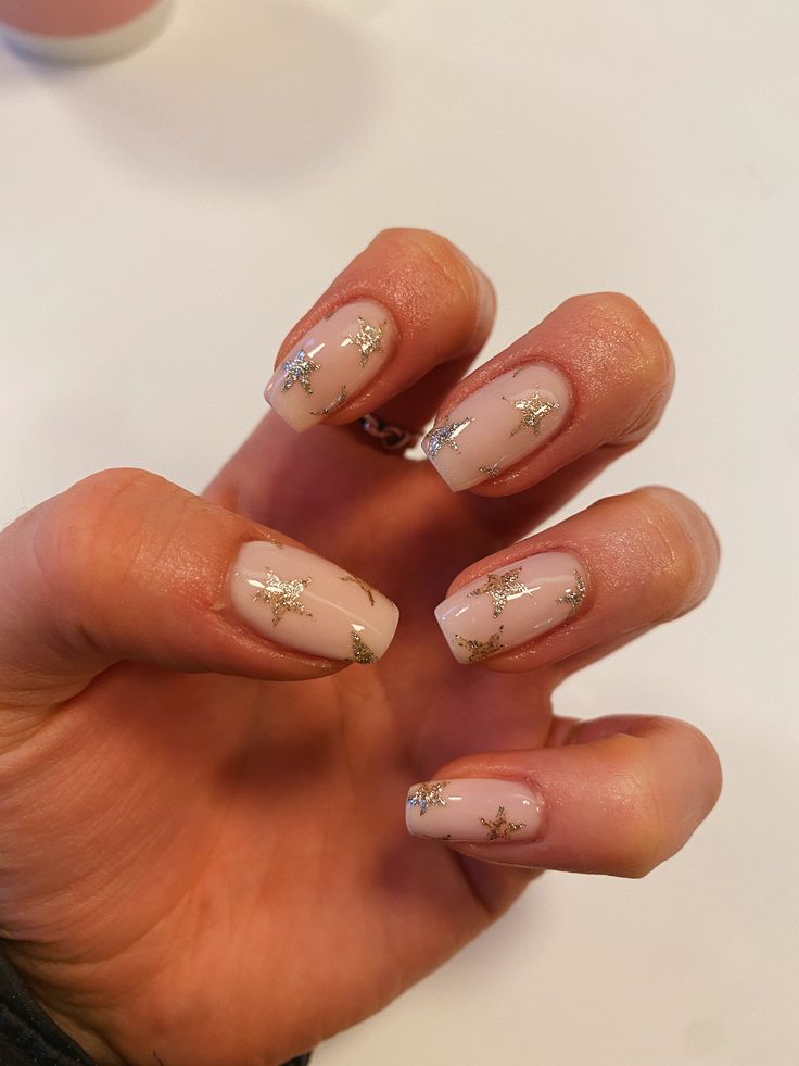 Sophisticated Nude Nails with Delicate Gold Star Accents for an Elegant Look.