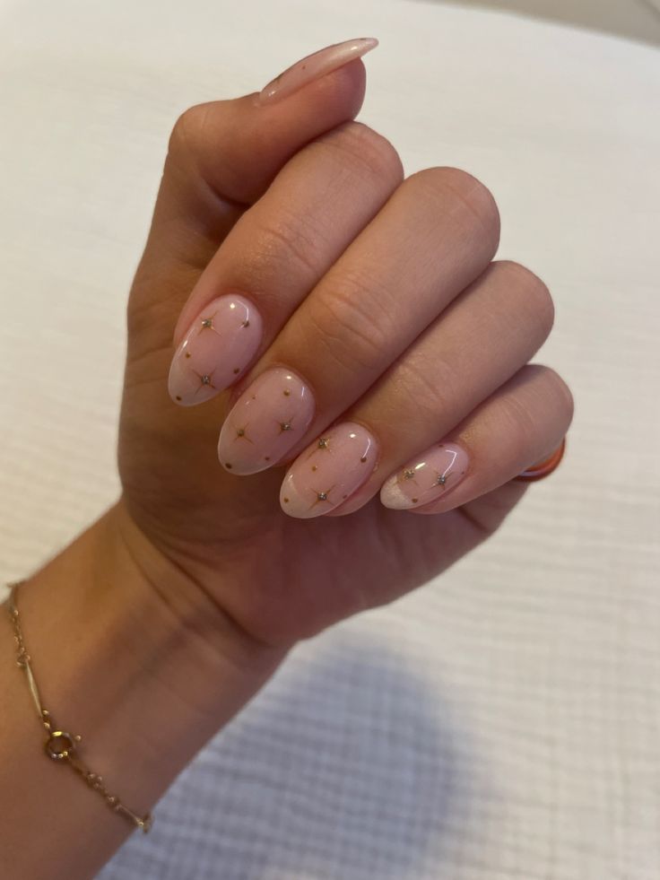 Charming Almond-Shaped Nail Design: Soft Pink Base with Golden Stars