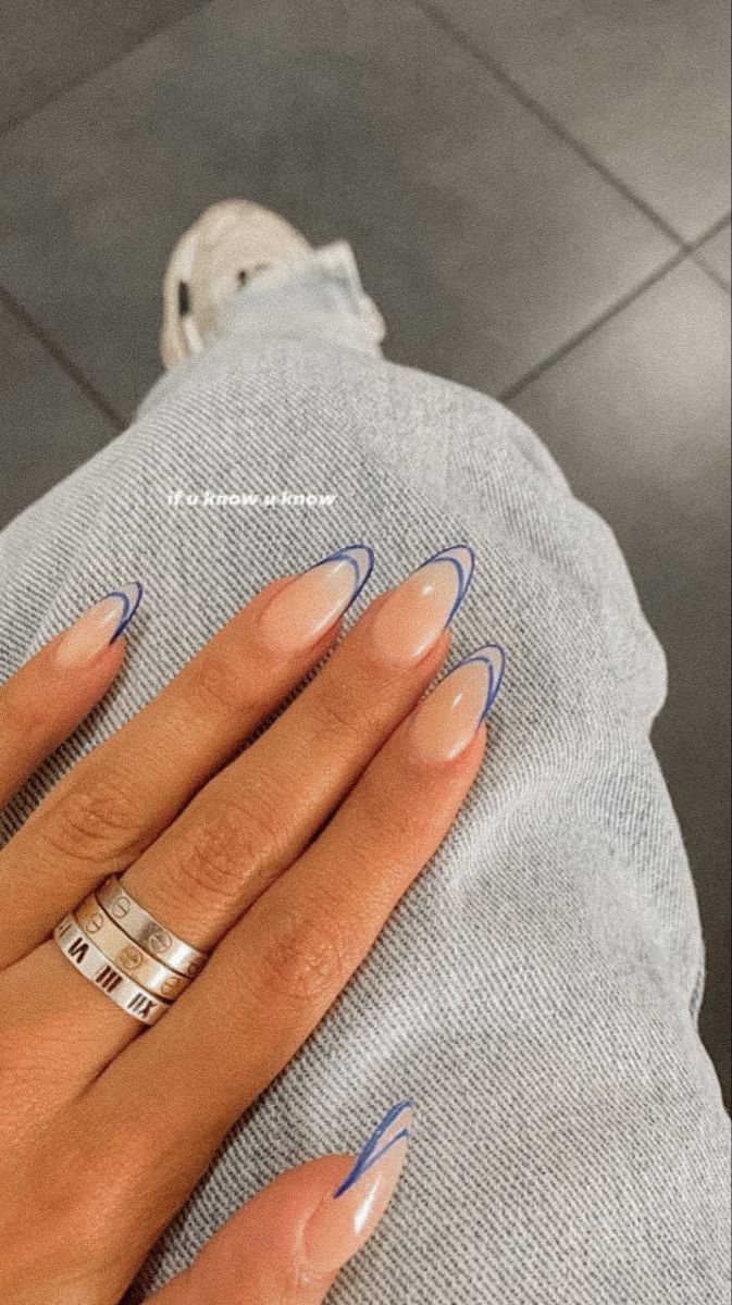 Chic Almond-Shaped Nails: Elegant Nude with Delicate Blue Tips and Stylish Rings.