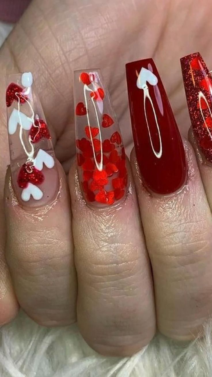 Playful and Romantic Colorful Nail Design with Clear Base, Red Hues, Heart-Shaped Embellishments, and Glittery Accents