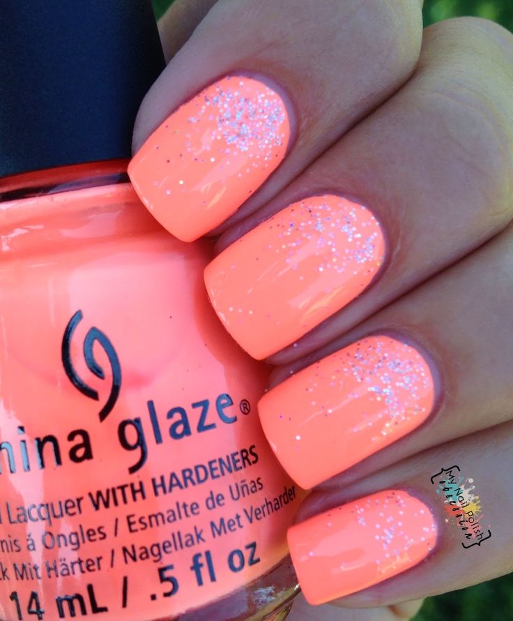 Cheerful Glossy Coral Nail Design with Sparkling Glitter Tips for a Trendy Summer Look.