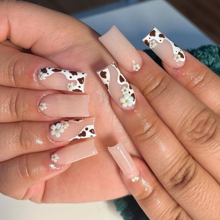 Playful Cowprint Nail Design with Elegant Floral Accents on Long Square Nails.