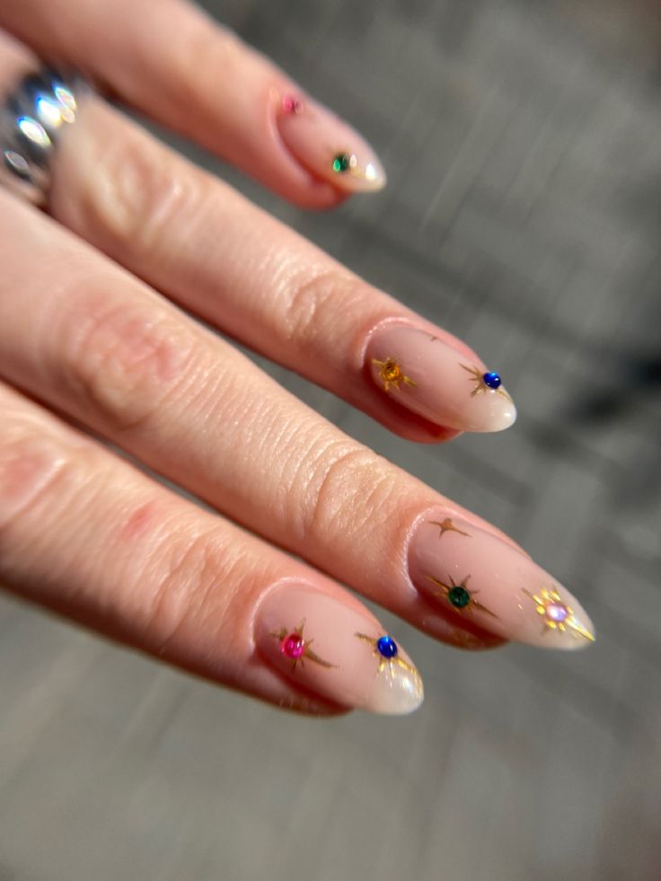 Elegant Nude Nail Design with Colorful Gem Accents and Playful Motifs.