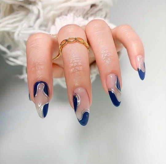 Elegant Navy Blue Nail Design with Fluid Patterns and Elongated Tips.