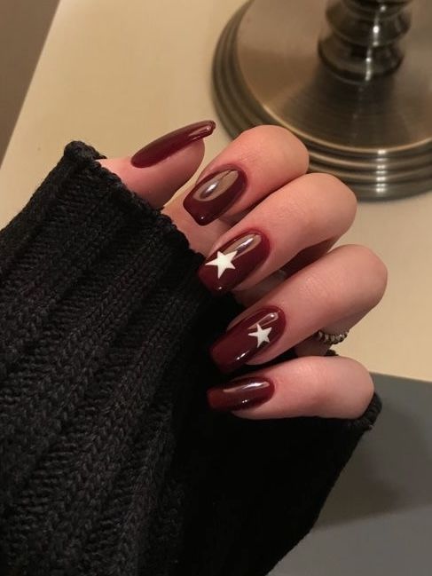 Charming Deep Burgundy Nail Design with Glossy Finish and Whimsical White Star Embellishments.