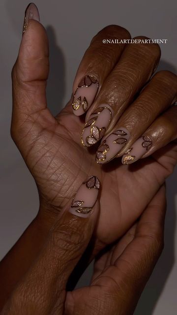 Sophisticated Nude Nail Design with Shimmering Gold and Bronze Leaf Patterns.