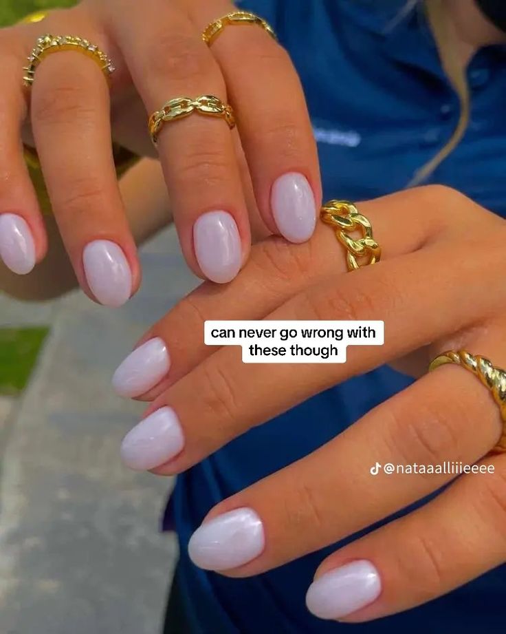 Elegant Pale Pink Nail Design Accentuated by Glamorous Gold Rings for a Timeless Look.