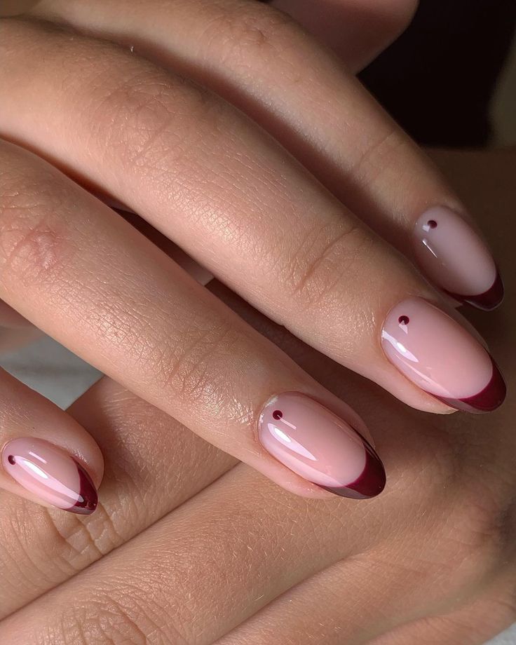 Sophisticated Nail Design: Soft Pink Base with Deep Burgundy Tips and Minimalistic Accents.