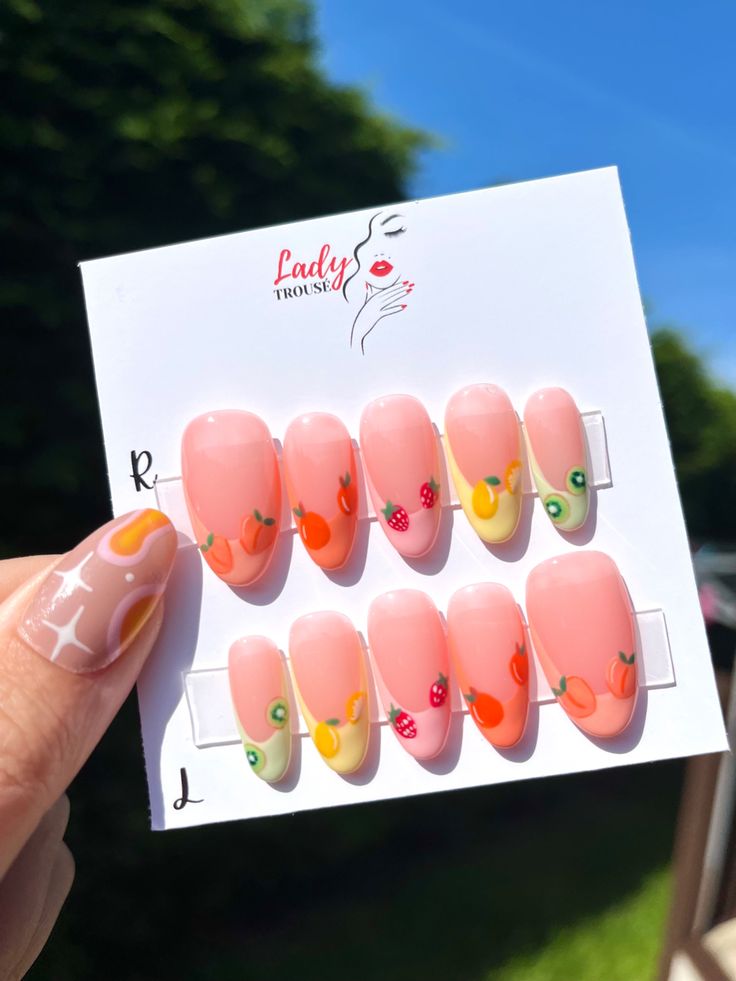 Cheerful Pastel Pink Nail Design with Playful Fruit Motifs for a Whimsical Summer Look