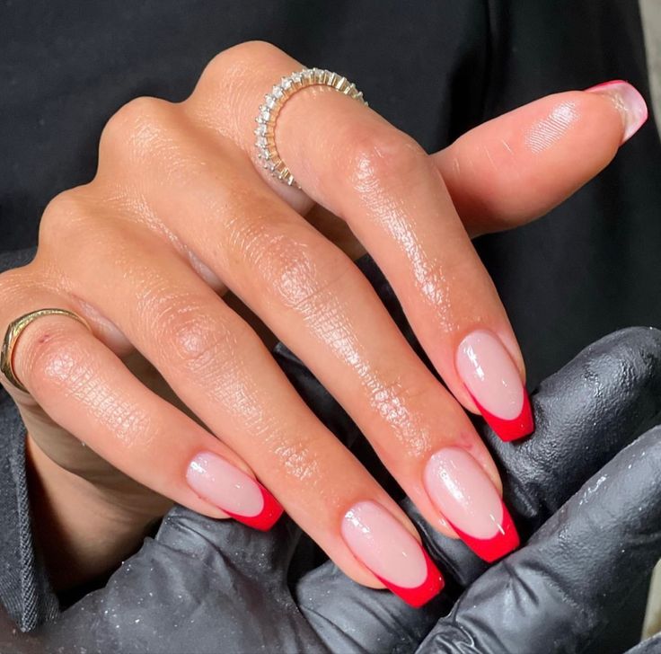 Sophisticated Almond-Shaped French Manicure with Subtle Nude Base and Bold Red Tips.