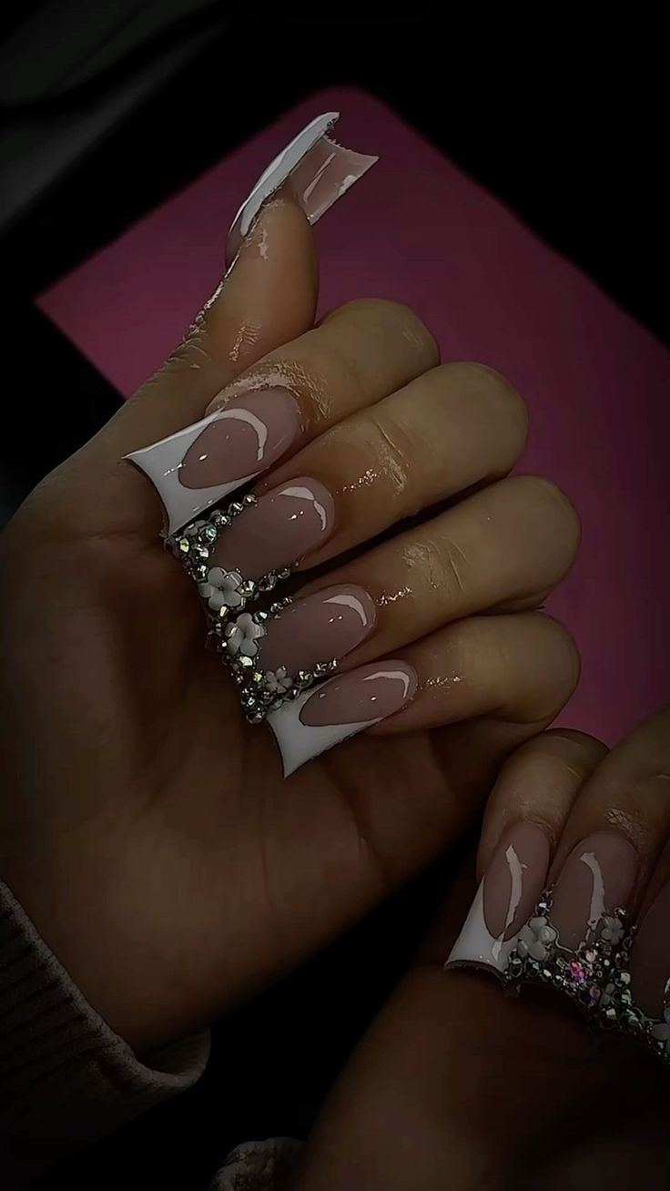 Chic Stiletto Nail Design: Nude Base with Elegant White Tips and Sparkling Accents.