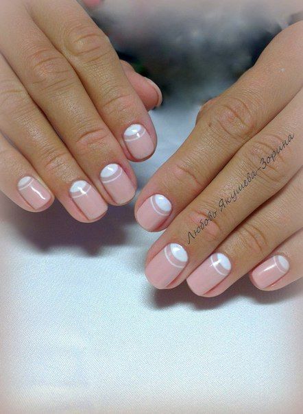 Chic Minimalist Nail Design: Soft Pink Base with White Geometric Half-Moon Patterns.