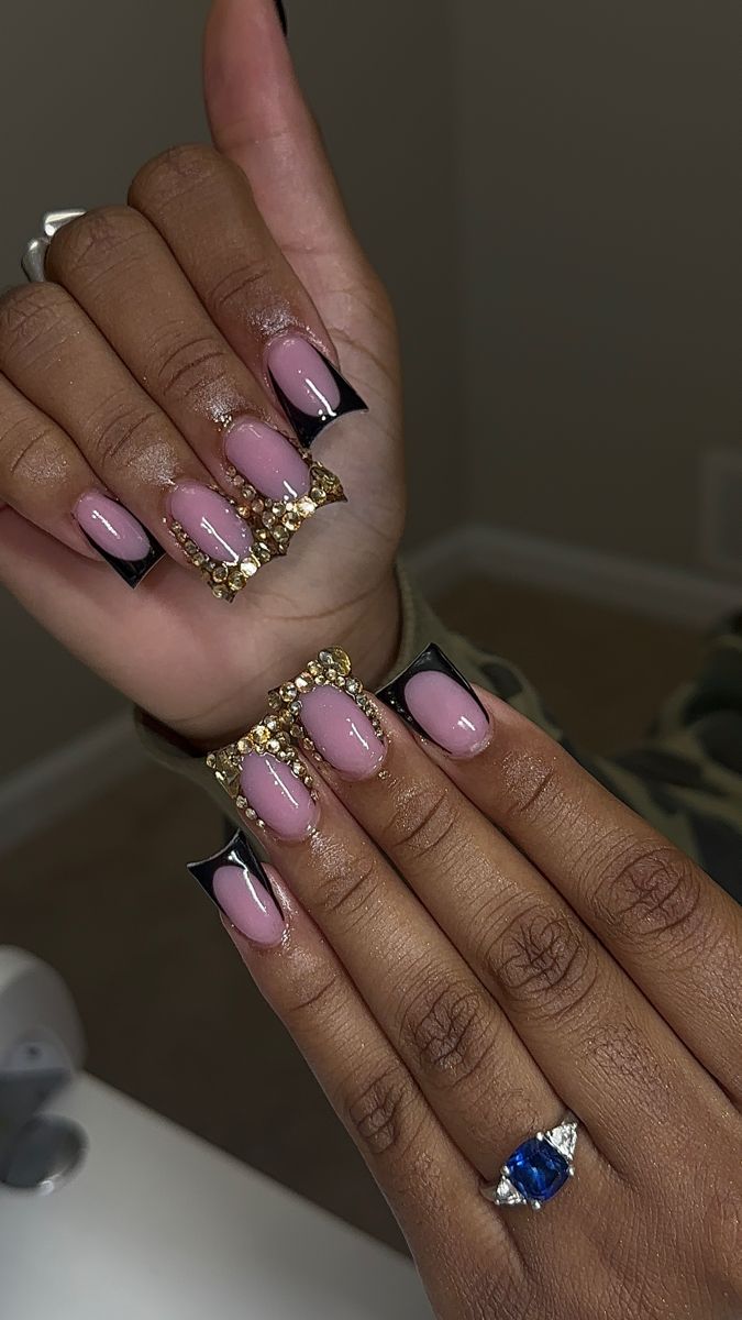 Chic Soft Pink Nails with Striking Black Tips and Glamorous Gold Accents.